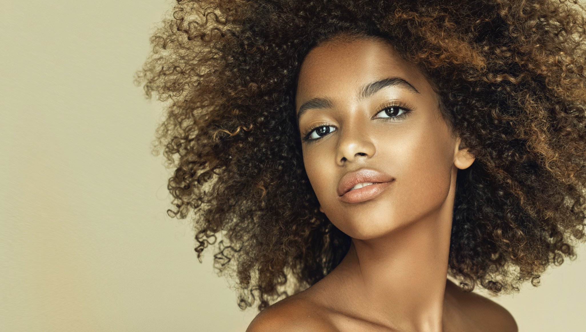 Natural Afro hair.Light, tender smile the face of young brown skinned woman. Afro beauty.